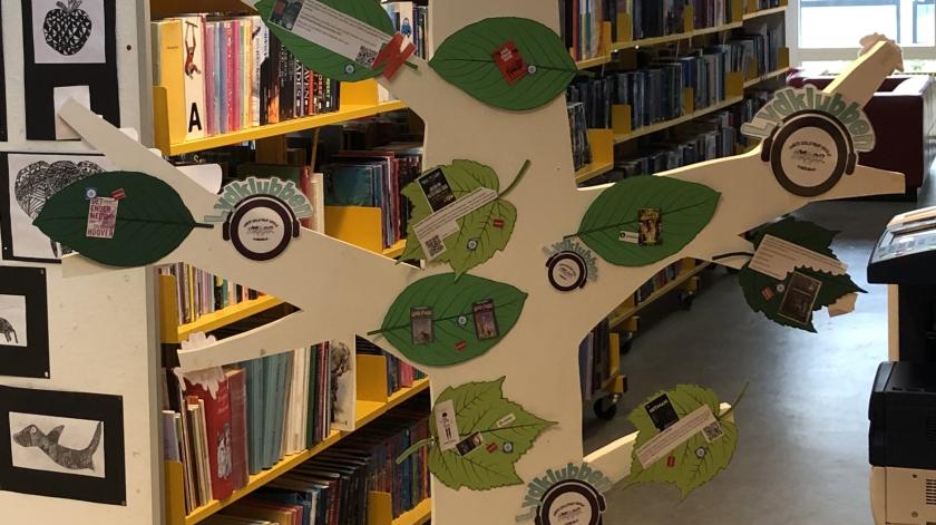 Udsnit af træ i skolebiblioteksmiljø med anbefalinger af lydbøger og podcast