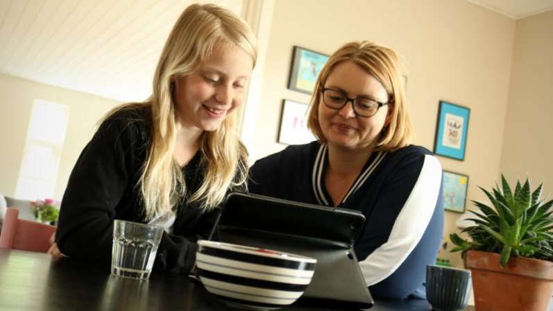 Arkiv foto: forældre og barn kigger på Ipad