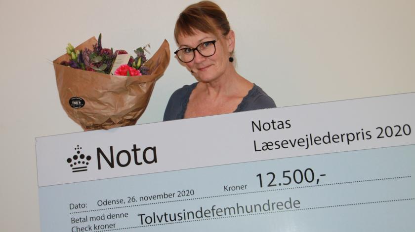 Glad kvinde med blomster og check på kr. 12.500 