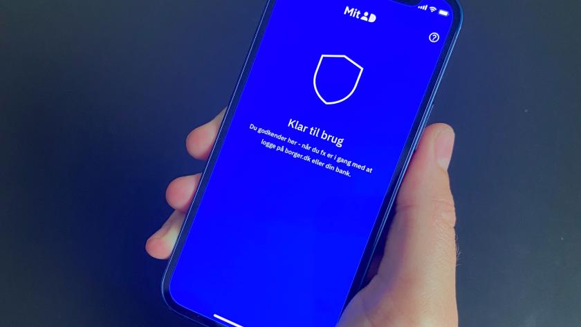 En hånd, der holder mobiltelefon, hvor MitID-appen er åbnet.